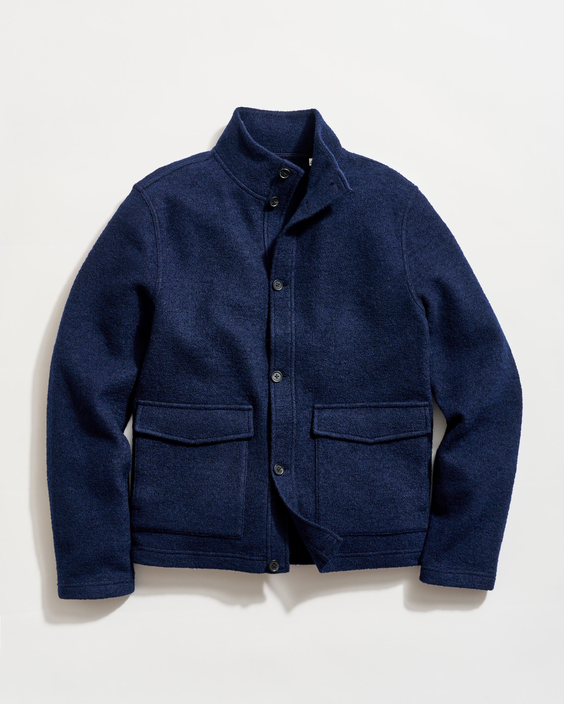 A navy blue wool jacket with a stand-up collar, button-front closure, and two large front flap pockets, laid flat on a white background.