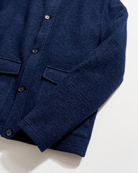 Navy blue textured wool jacket with black buttons and flap pockets, laid flat on a white background, showing the front and part of one sleeve.