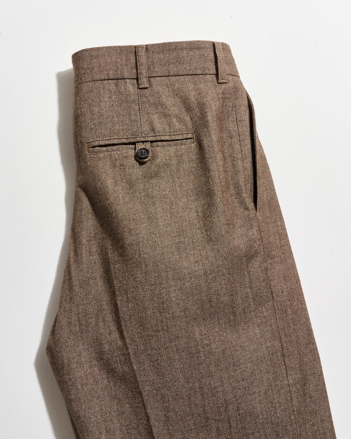 A pair of brown dress pants with a single back pocket featuring a button closure, shown neatly folded on a white background.