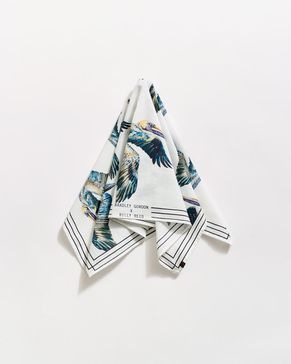 A folded white handkerchief hangs against a white background, featuring colorful bird illustrations and black border lines. The text Bradley Gordon and Billy Reid is visible near one corner.