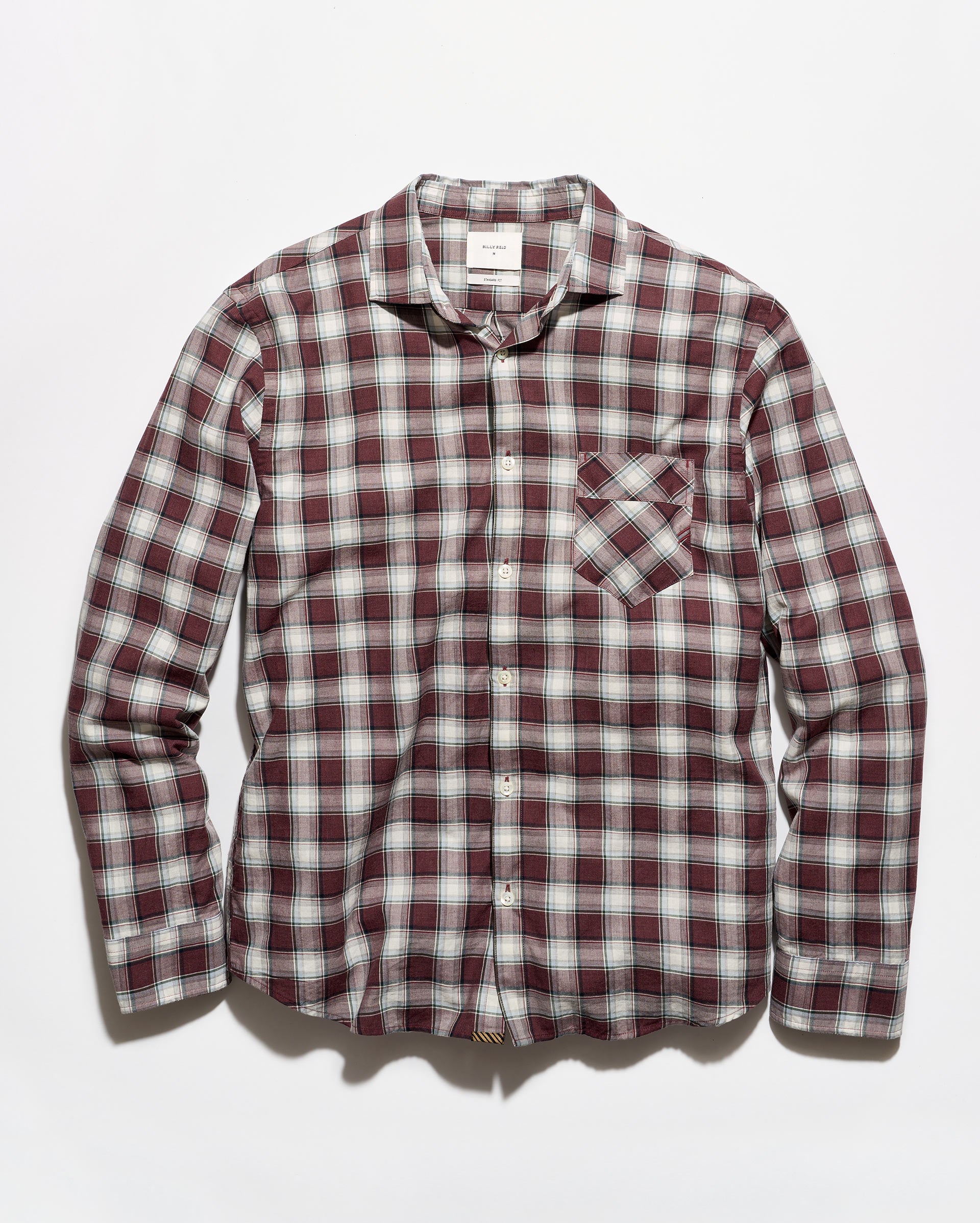 A long-sleeve button-up plaid shirt in a burgundy, white, and gray checkered pattern, featuring a single chest pocket, laid flat against a light gray background.