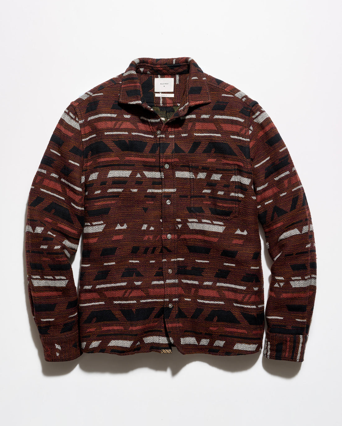 A long-sleeve button-up shirt with a geometric pattern in dark red, black, and off-white, laid flat against a light gray background.