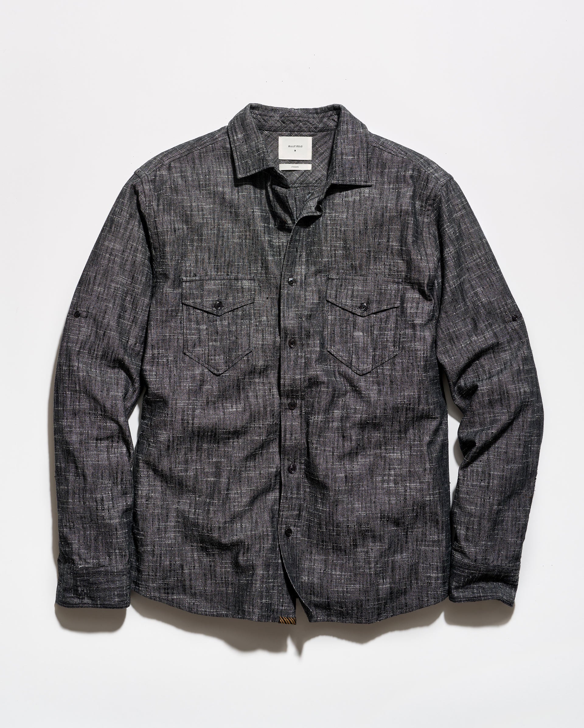 A dark gray textured long-sleeve button-up shirt with two chest flap pockets, laid flat against a white background.