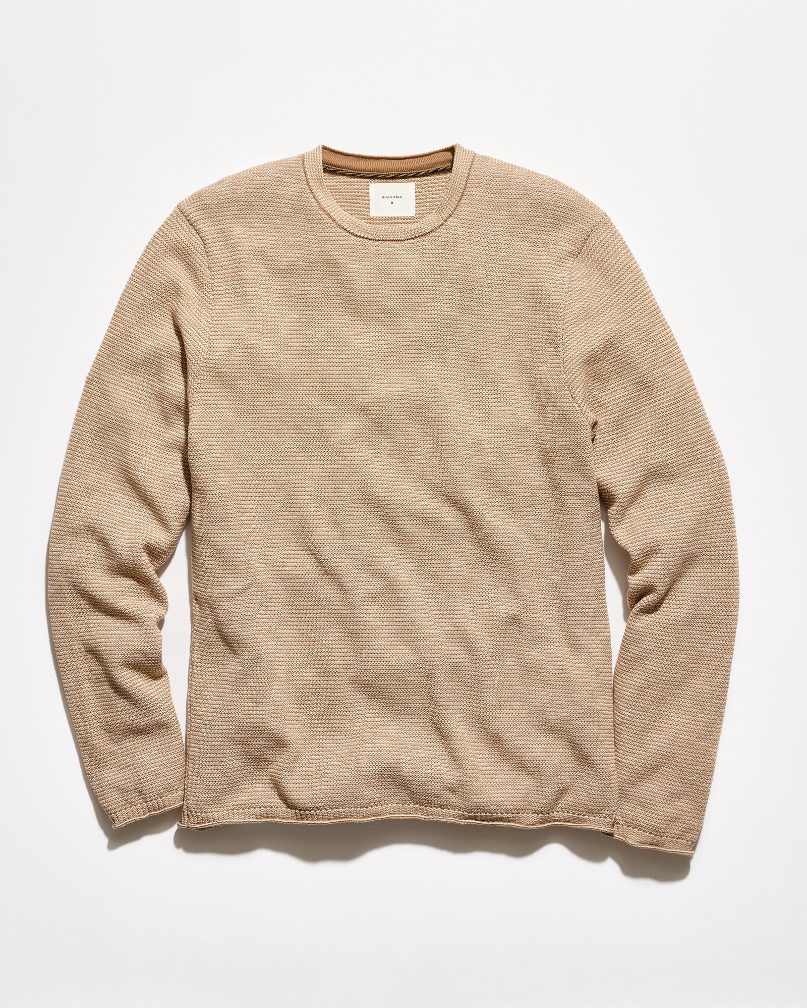 A beige ribbed long-sleeve crewneck sweater laid flat against a clean white background.