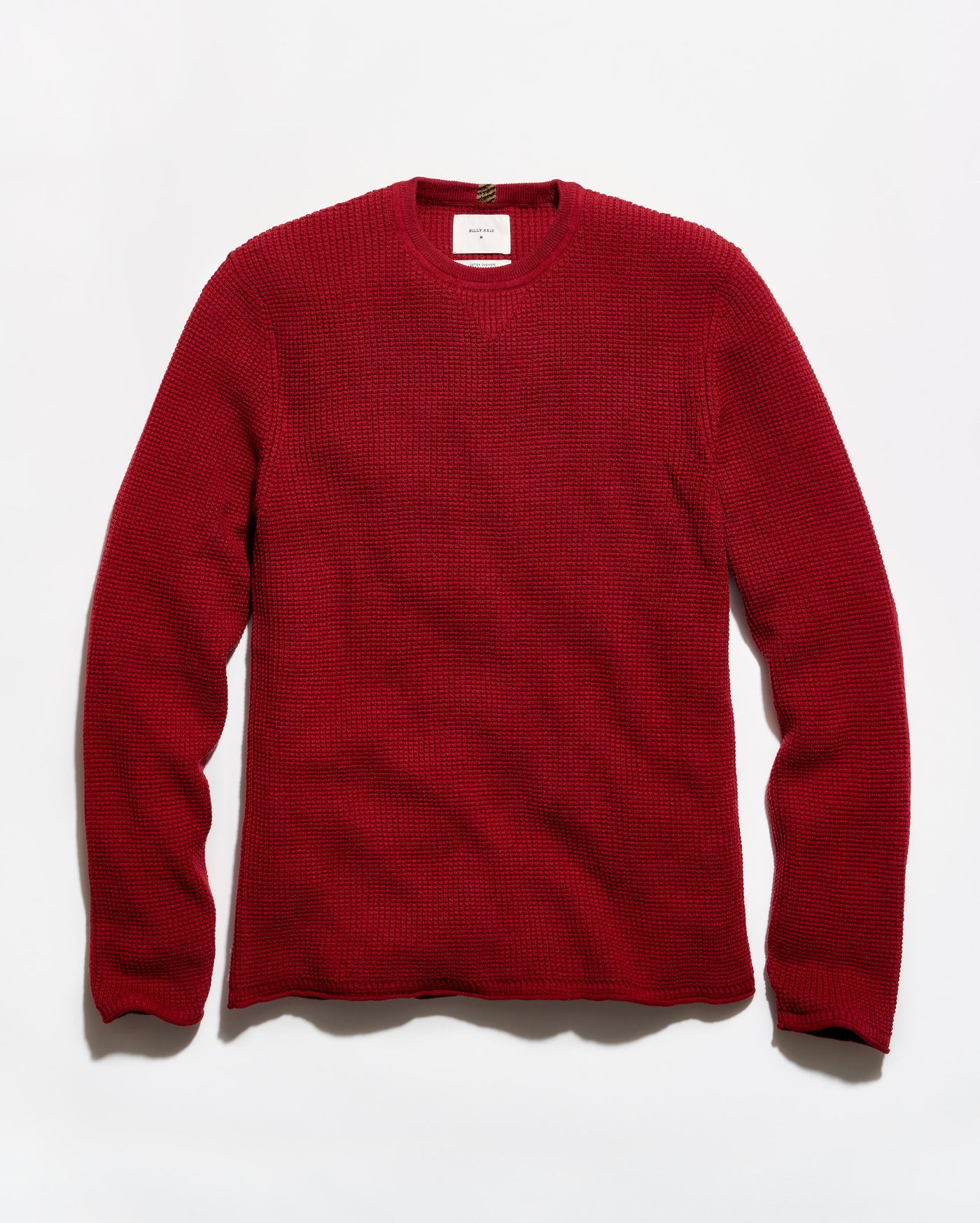 A red waffle-knit crewneck sweater laid flat against a white background.
