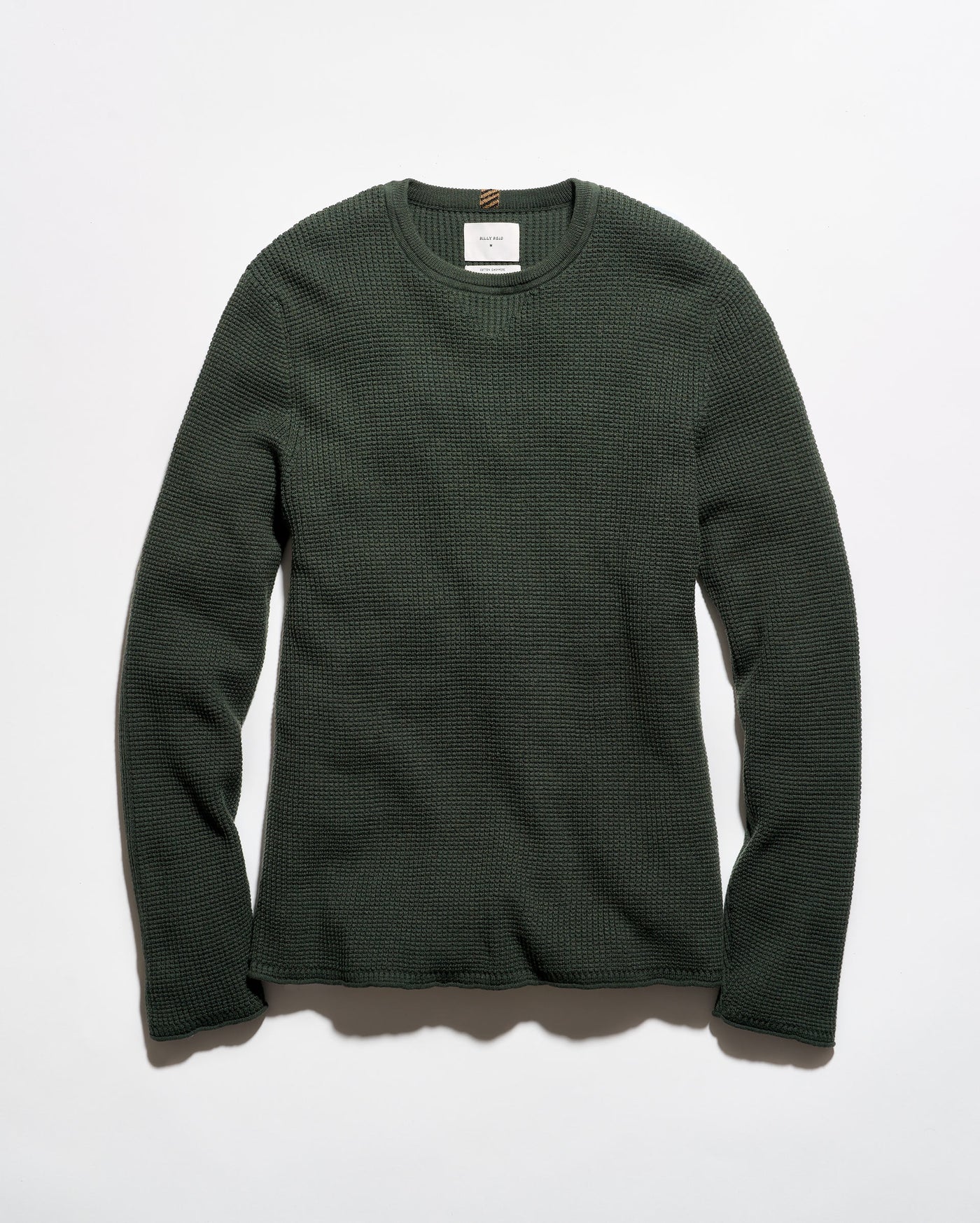 A dark forest green waffle-knit long-sleeve crewneck sweater laid flat against a light gray background.