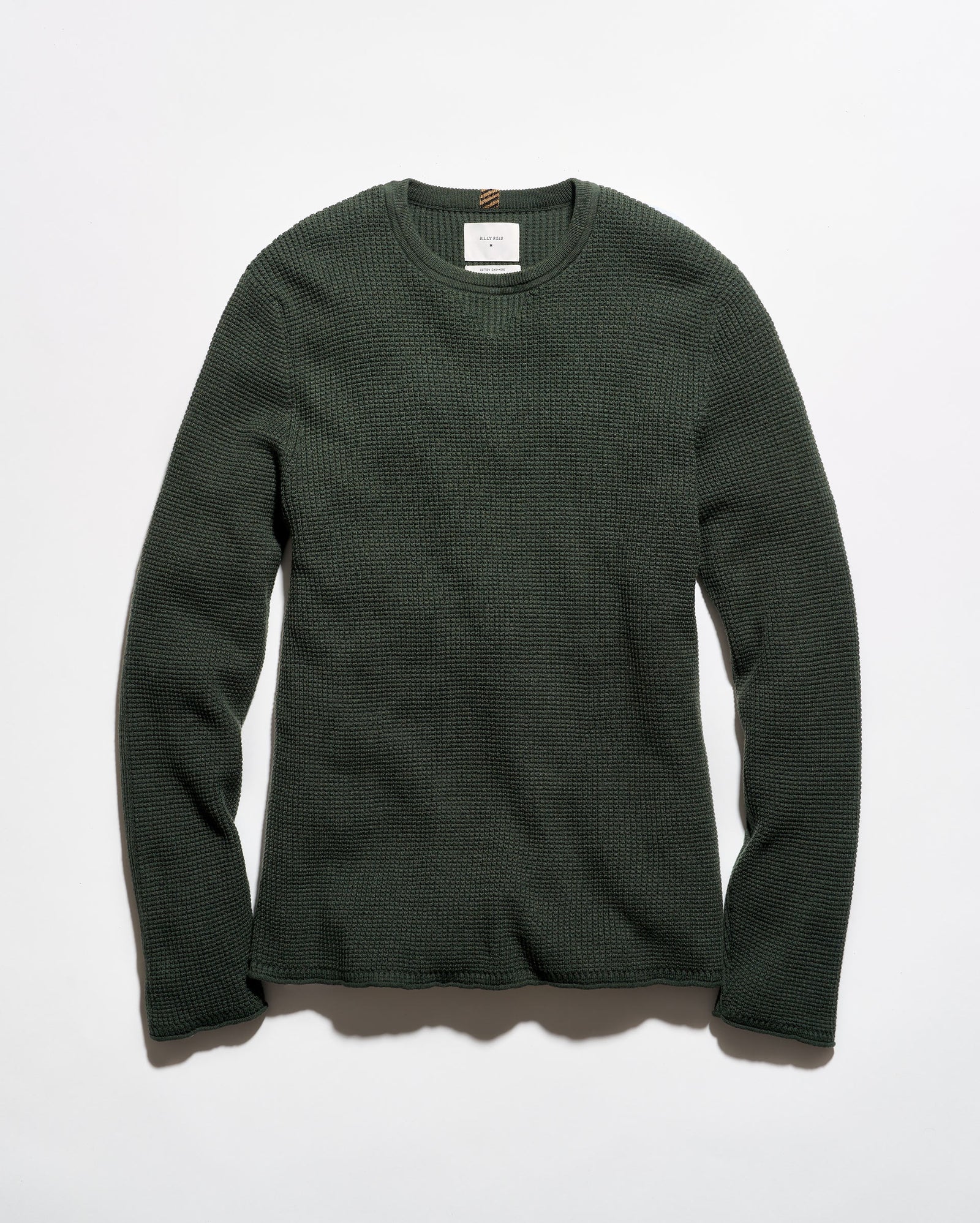 A dark forest green waffle-knit long-sleeve crewneck sweater laid flat against a light gray background.