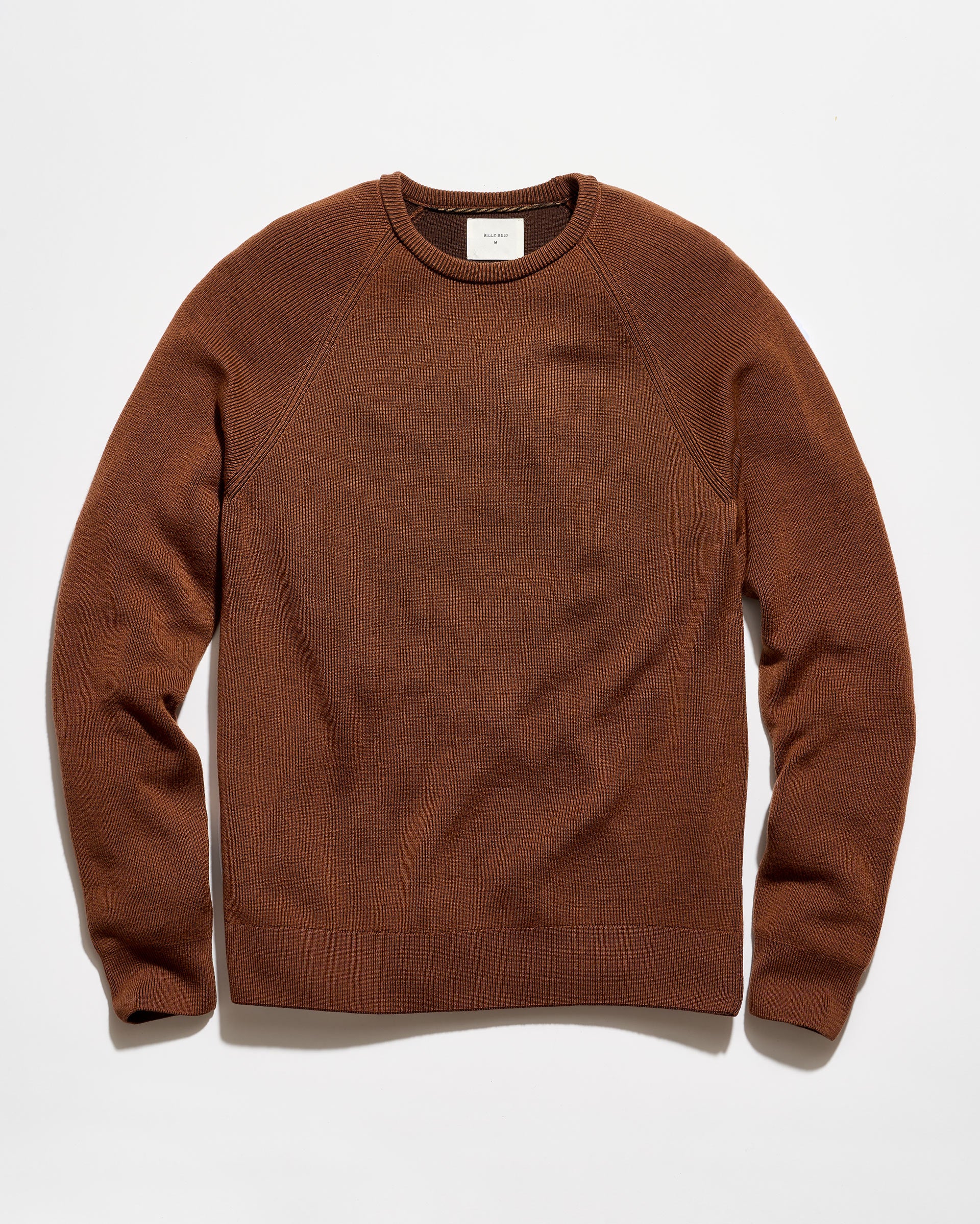 A brown crewneck knit sweater with raglan sleeves, laid flat against a clean white background.