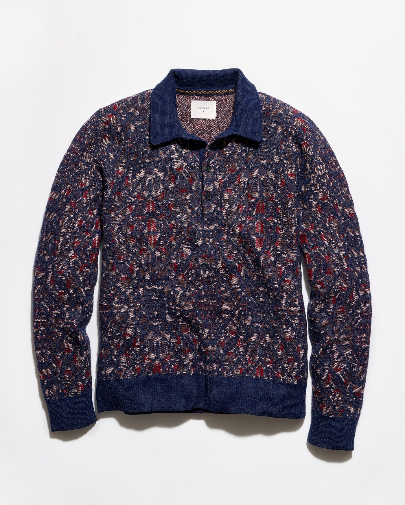 A long-sleeve knit polo-style sweater with an intricate geometric pattern in navy blue, burgundy red, and beige, featuring solid navy ribbed trim on the collar, cuffs, and hem.