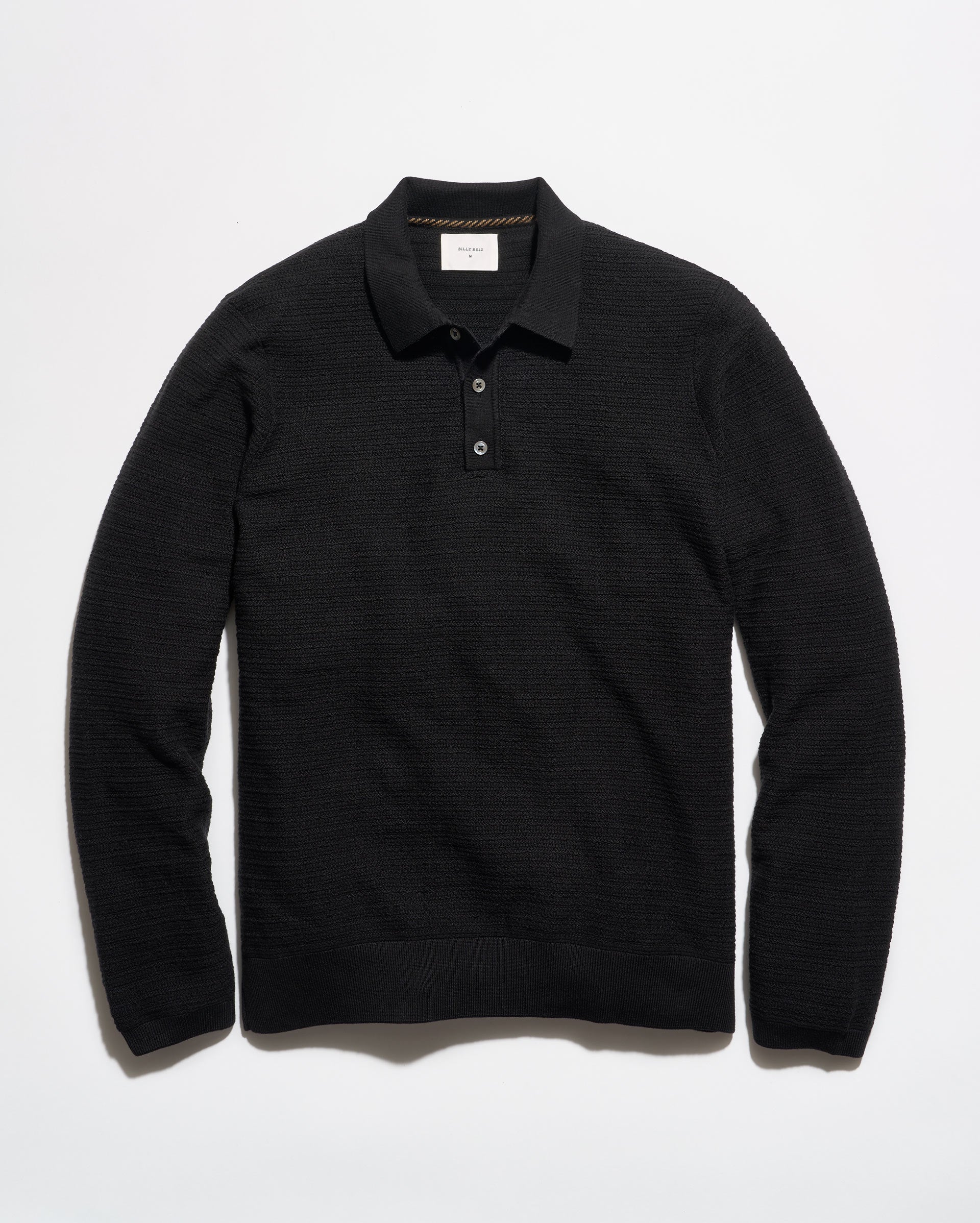 A black long-sleeve knit polo shirt with a textured horizontal rib pattern, laid flat against a clean white background.