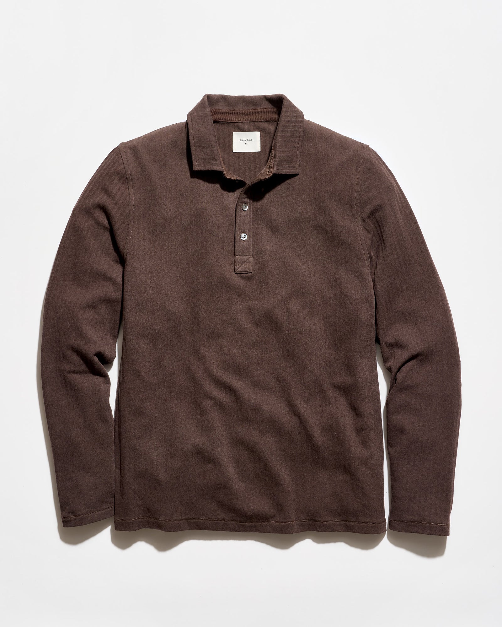 A dark brown ribbed long-sleeve polo shirt with a three-button placket, laid flat against a light off-white background.