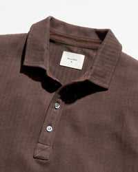 Close-up of a dark brown textured polo shirt by Billy Reid, showing the collar, three-button placket, and a white brand label.