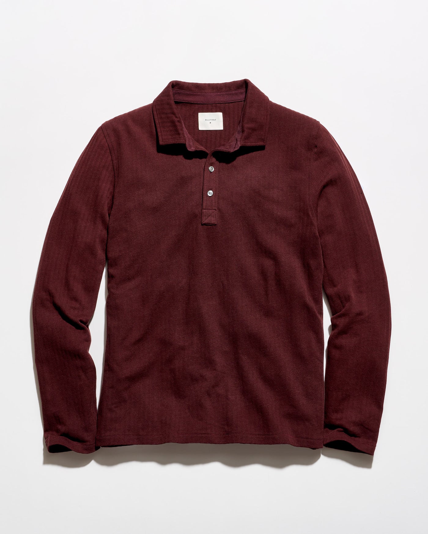 A long-sleeve polo shirt in a deep burgundy color, laid flat against a clean white background.