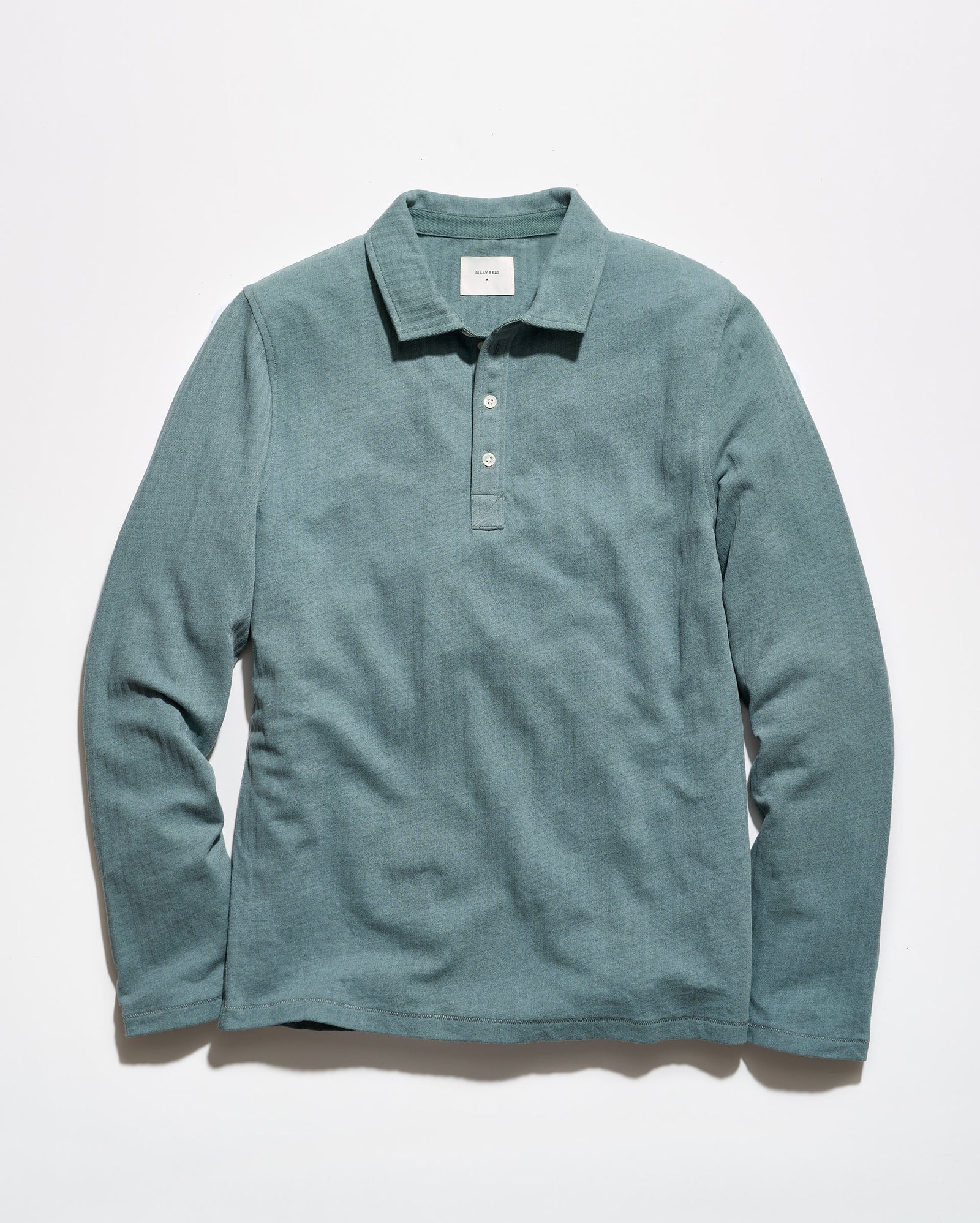 A long-sleeve polo shirt in a muted teal-green color, laid flat against a clean white background.