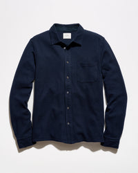 A dark navy blue long-sleeve button-up shirt with a single chest pocket, laid flat against a light off-white background.