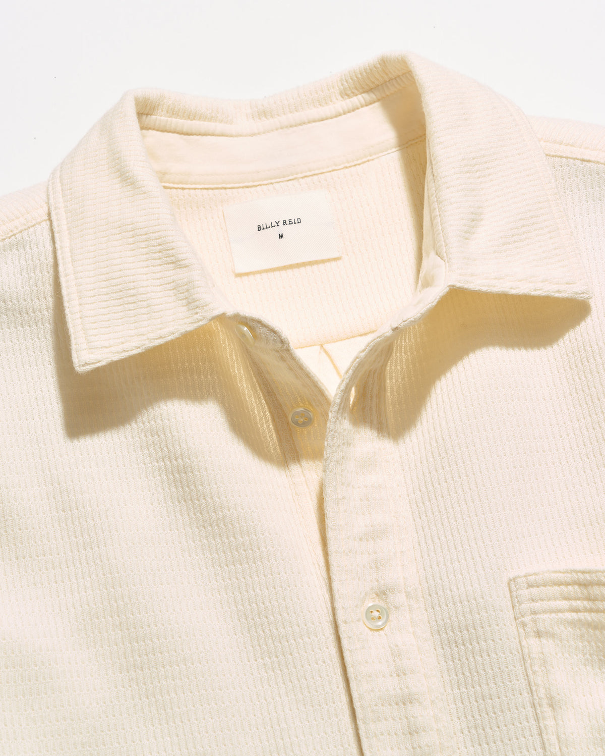 Close-up of a cream-colored textured button-down shirt collar with a visible 'BILLY REID' neck label.