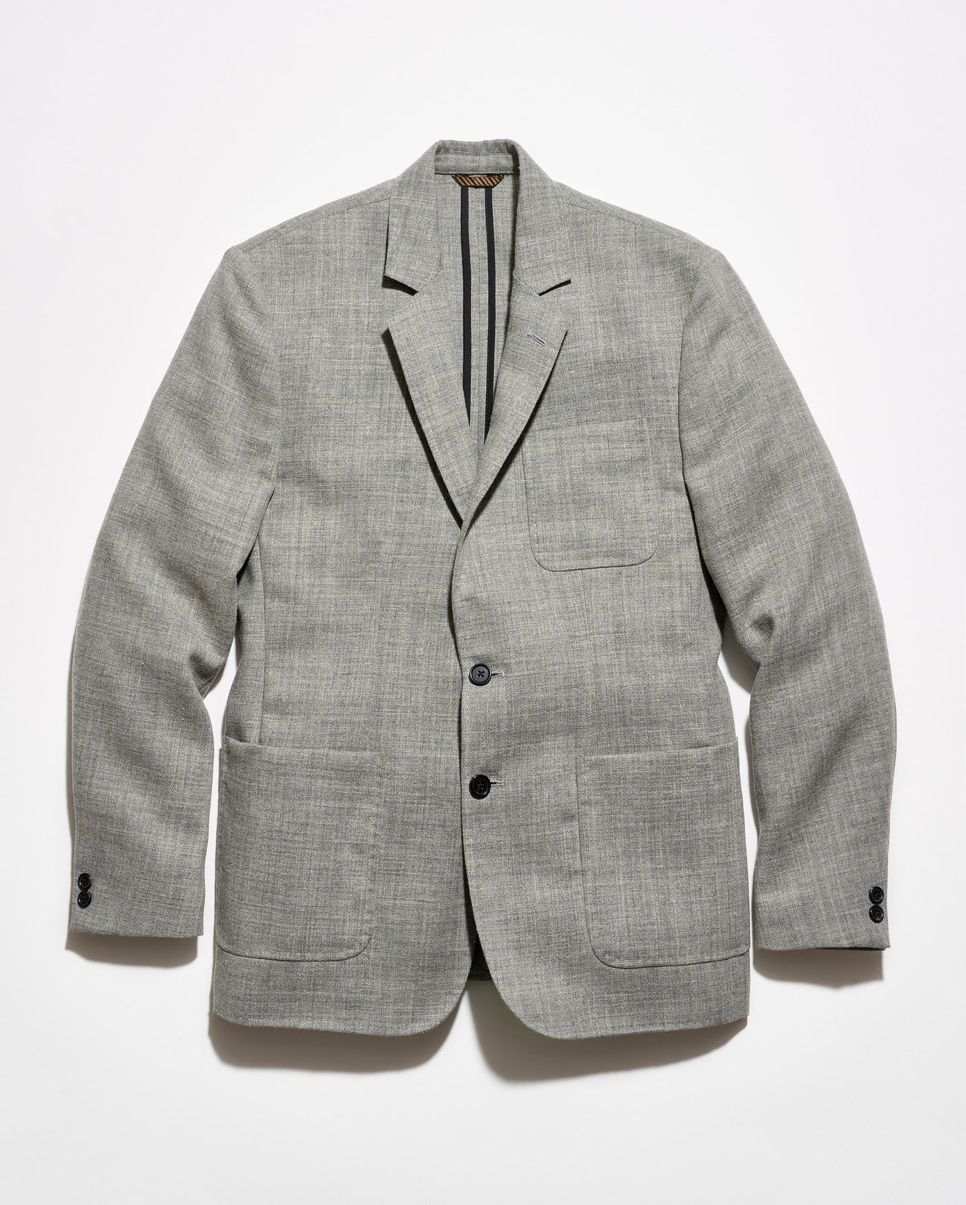 A light gray textured blazer with black tape reinforcement at the back interior, featuring a two-button closure and two front patch pockets, displayed flat against a white background.