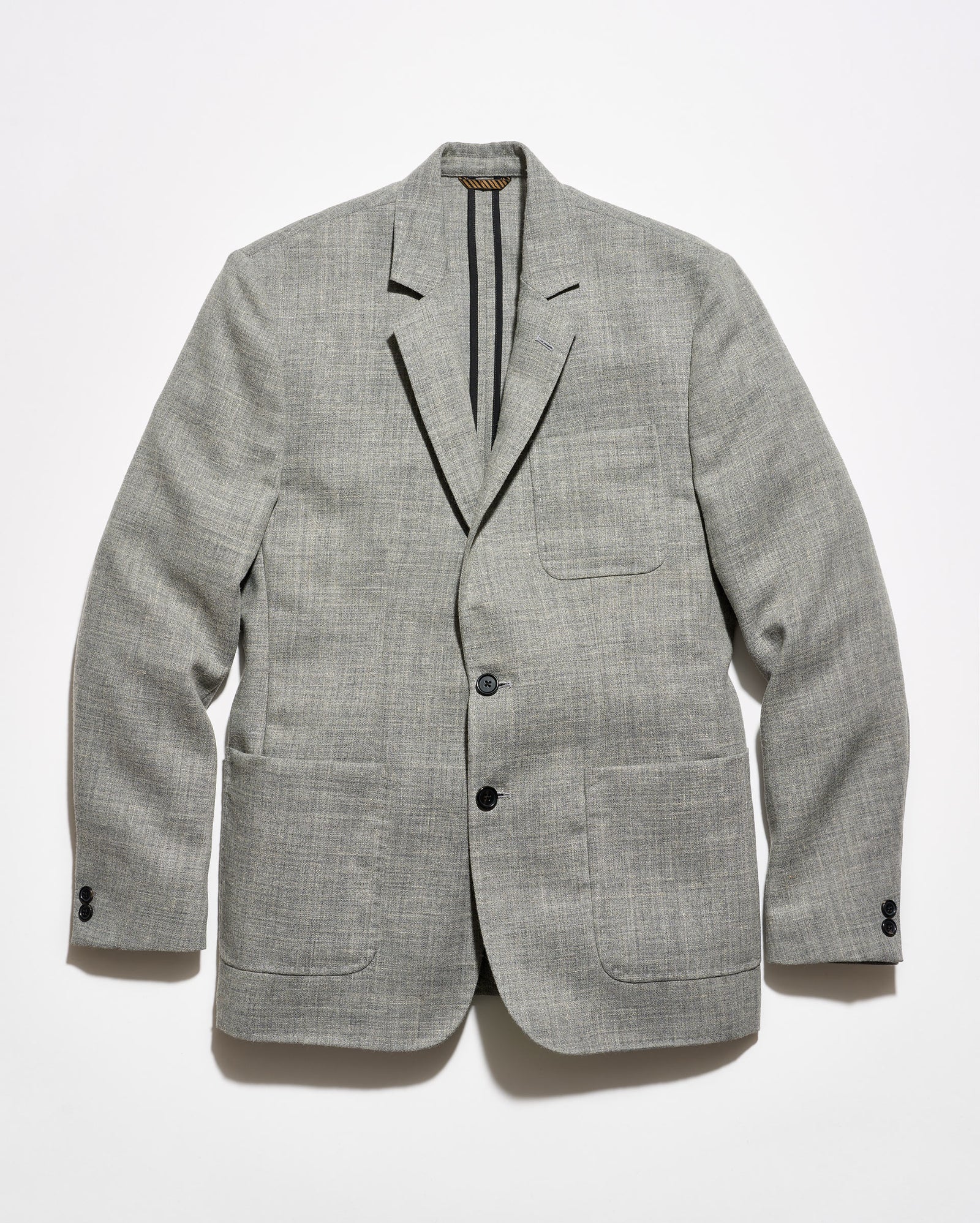 A light gray textured blazer with black tape reinforcement at the back interior, featuring a two-button closure and two front patch pockets, displayed flat against a white background.