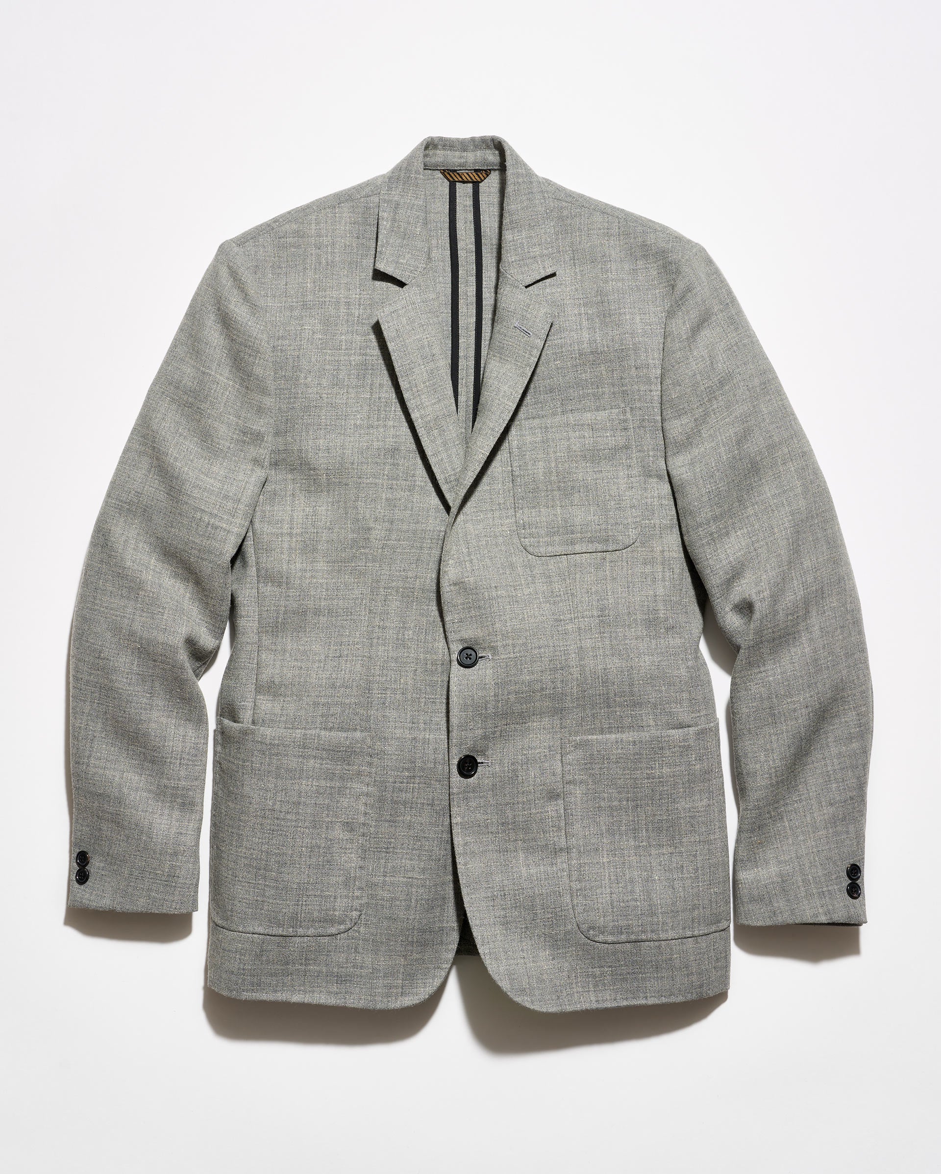 A light gray textured blazer with black tape reinforcement at the back interior, featuring a two-button closure and two front patch pockets, displayed flat against a white background.