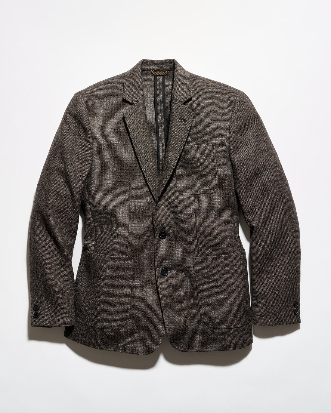 A men's plaid overshirt jacket featuring a navy, beige, and gray tartan pattern, button-up front, and two large diagonal welt pockets on the lower front.