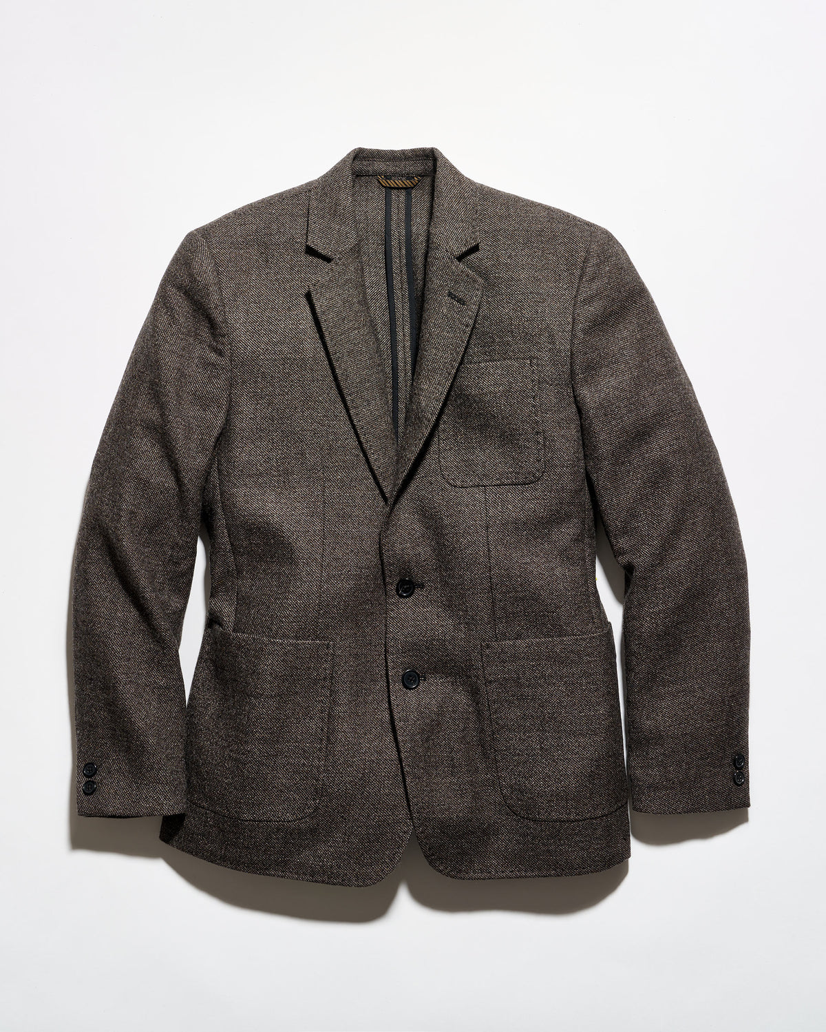 A men's plaid overshirt jacket featuring a navy, beige, and gray tartan pattern, button-up front, and two large diagonal welt pockets on the lower front.