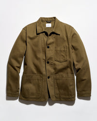 An olive green corduroy utility jacket with a pointed collar, black snap-button front, and four front pockets, laid flat against a white background.