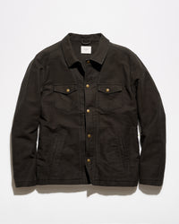 A dark brown canvas utility jacket with brass buttons, laid flat against a light gray background.