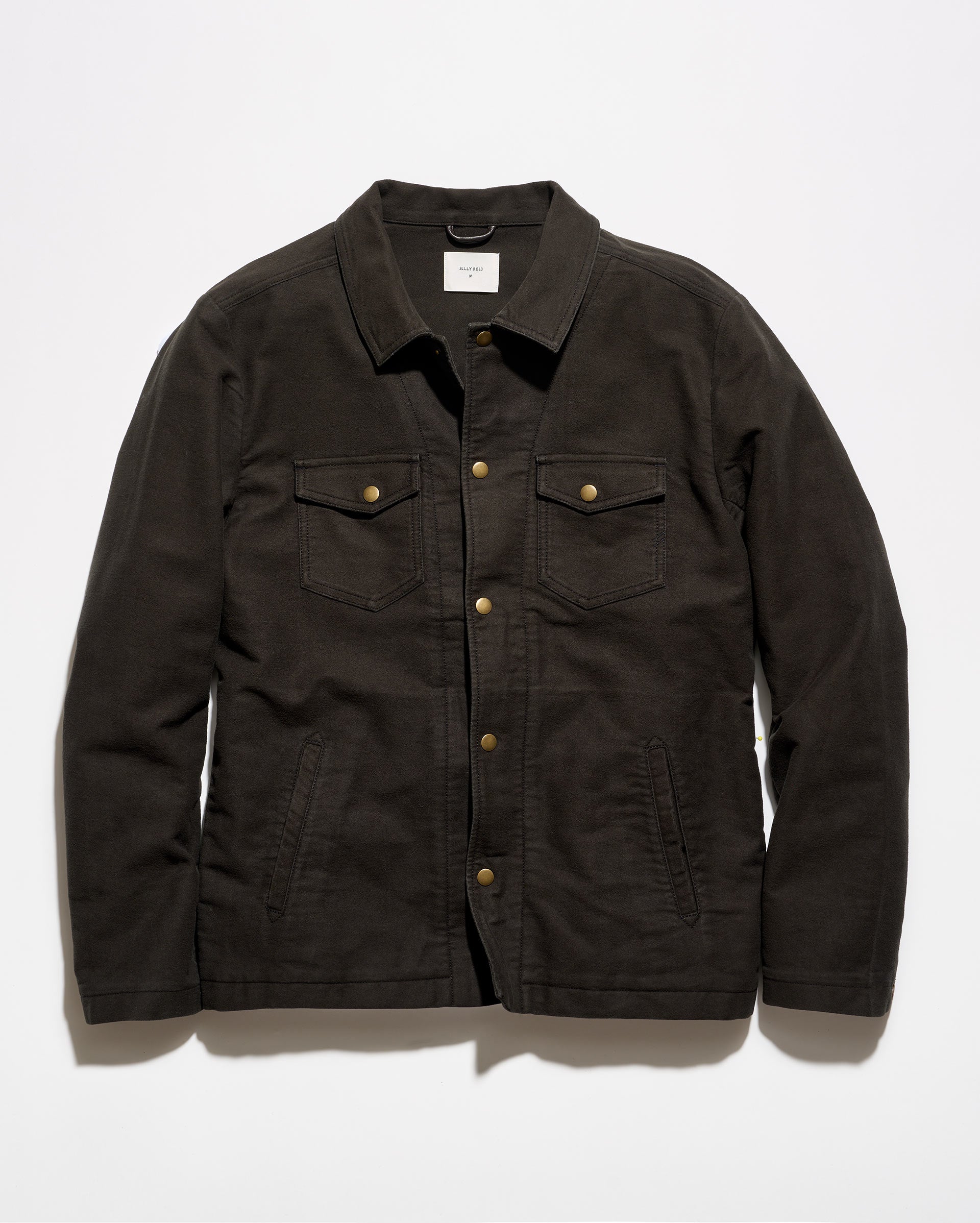 A dark brown canvas utility jacket with brass buttons, laid flat against a light gray background.