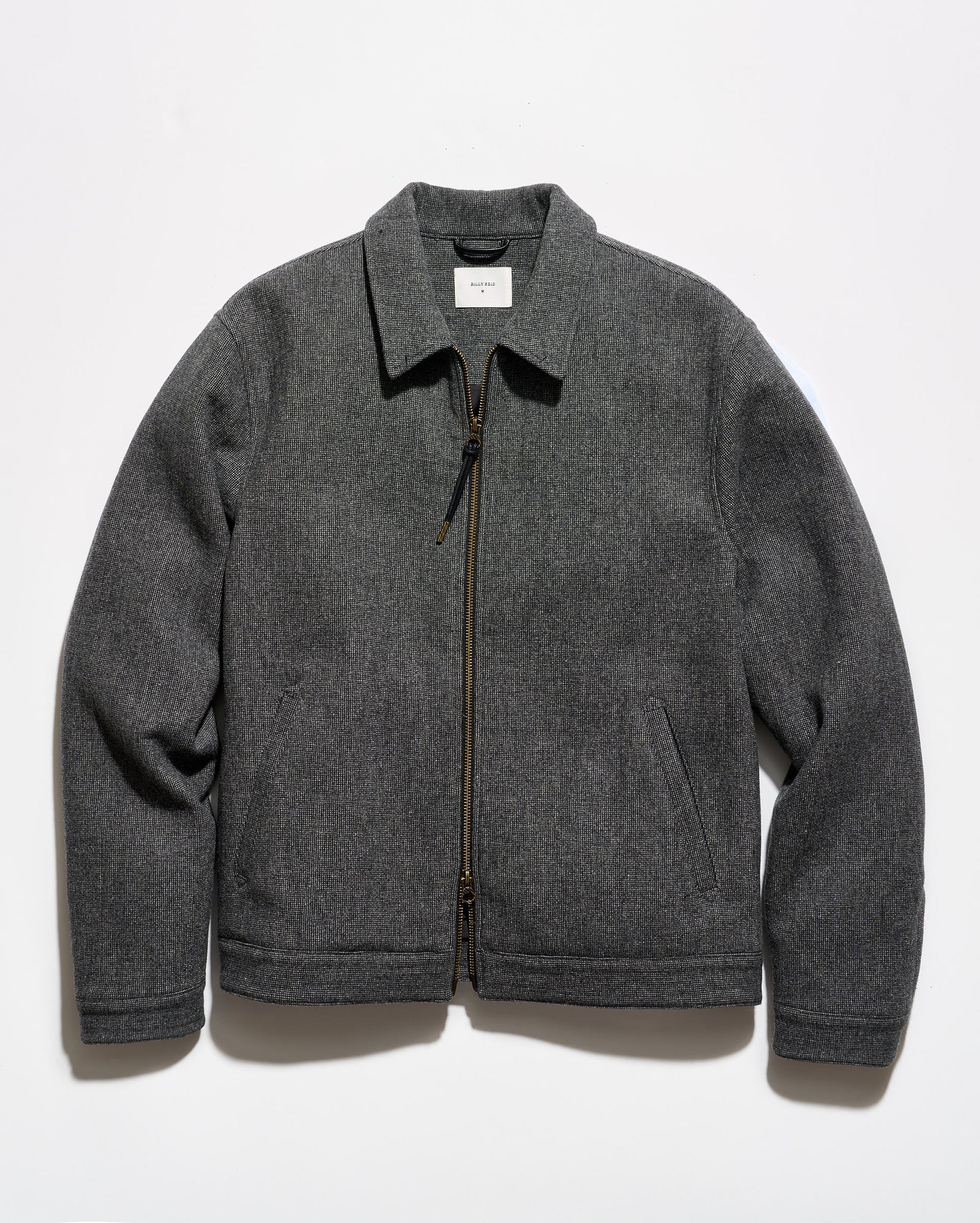 A dark gray zip-up jacket with a pointed collar and side pockets, laid flat against a white background.