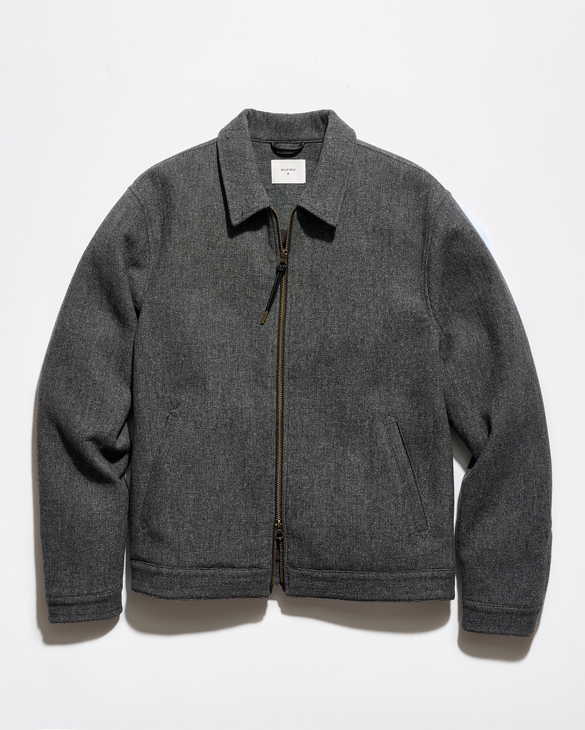 A dark gray zip-up jacket with a pointed collar and side pockets, laid flat against a white background.