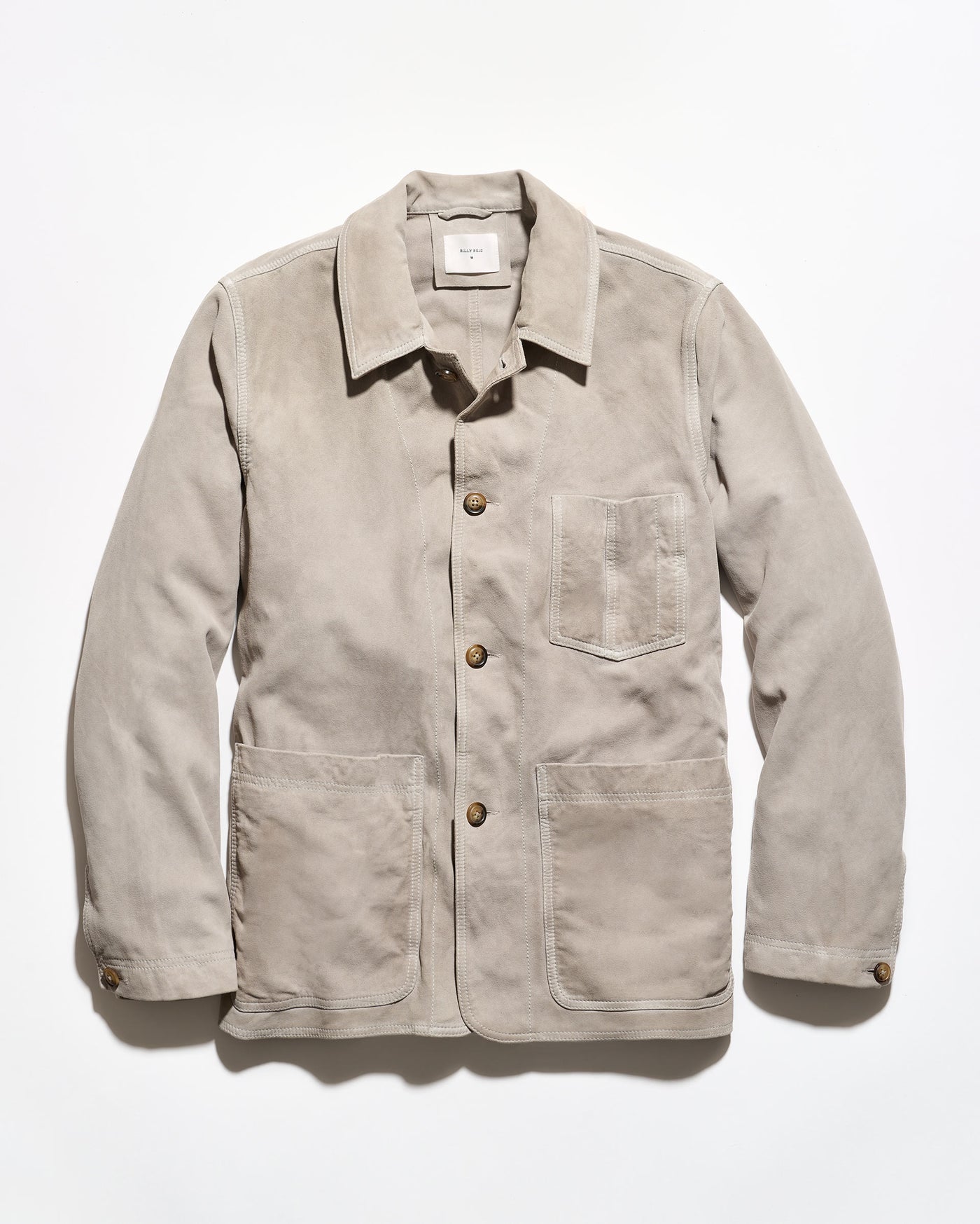 A light beige corduroy utility jacket with a pointed collar, button front, and three front pockets, displayed flat against a white background.