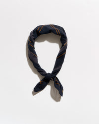 A navy blue silk scarf with thin gold stripes, knotted and looped to display its pattern, set against a plain white background.