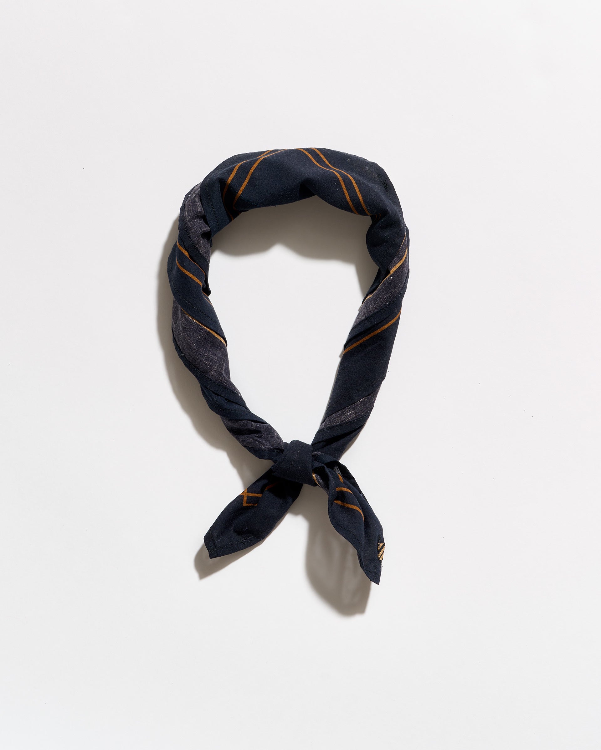 A navy blue silk scarf with thin gold stripes, knotted and looped to display its pattern, set against a plain white background.