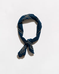 A navy blue silk scarf with a white geometric pattern, tied in a loop and knot, displayed on a clean white background.