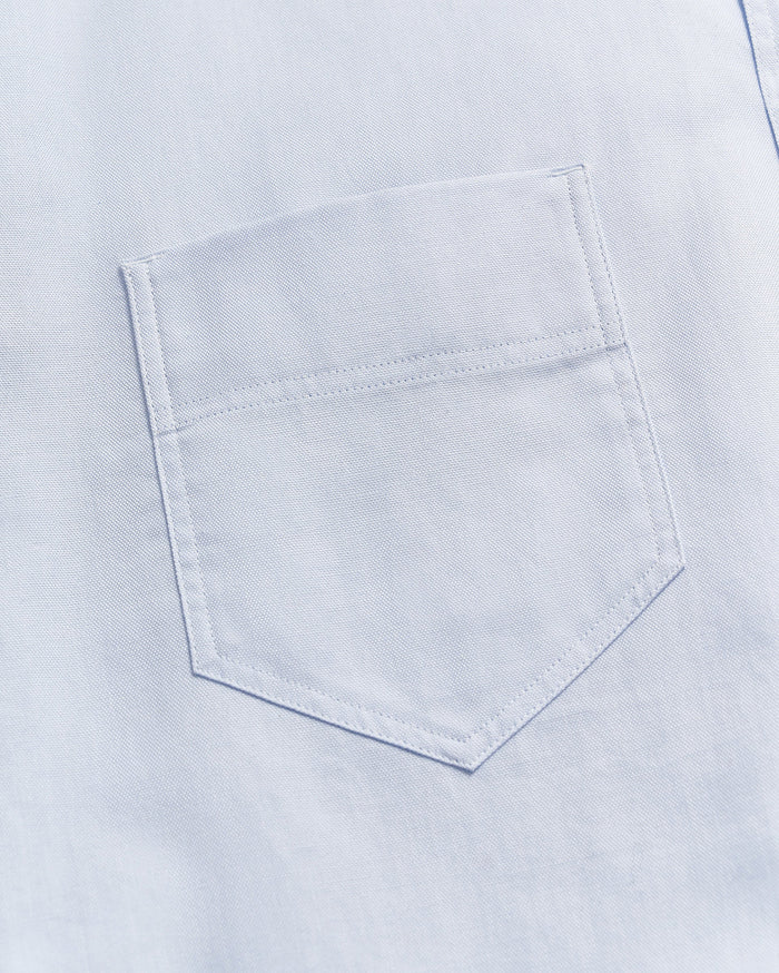 Close-up of a light blue fabric with a single, neatly stitched chest pocket visible in the center of the image.