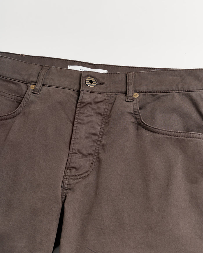 A close-up view of the waistband and upper section of brown pants with visible pockets, belt loops, and a button closure against a white background.