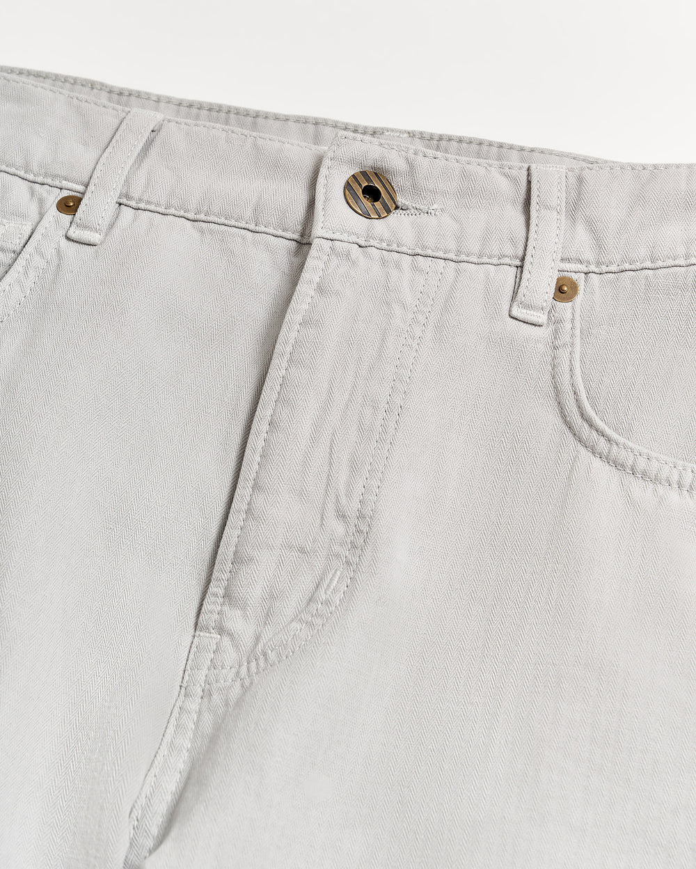 Close-up of the waist and upper leg area of light grey jeans with visible stitching, belt loops, a front button, and part of the pockets on a white background.