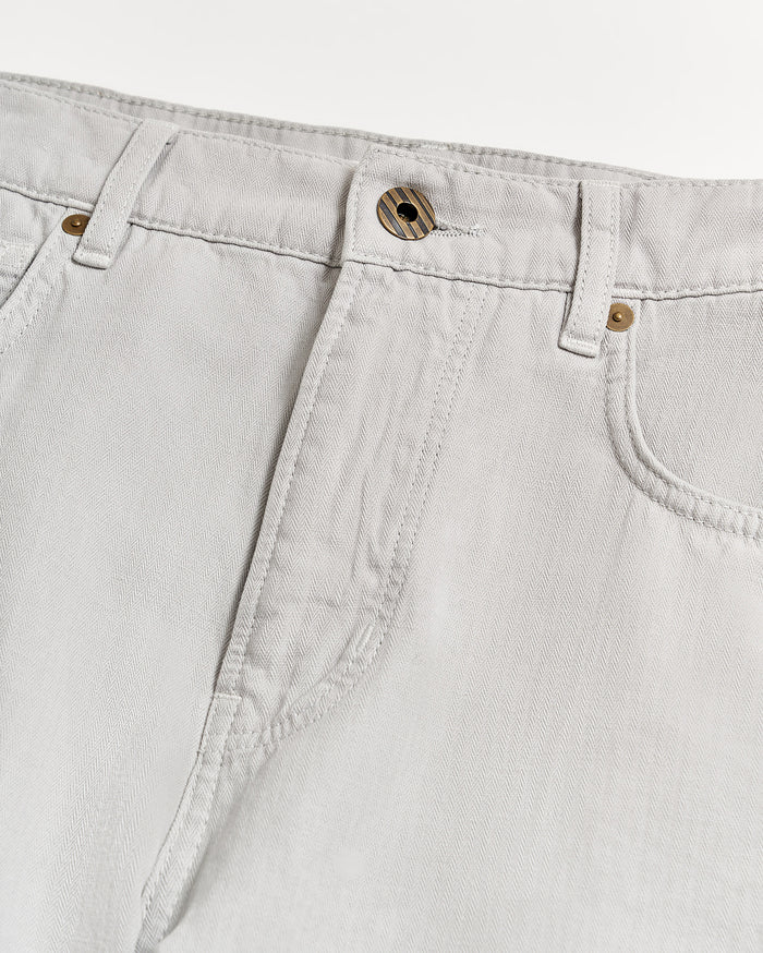 Close-up of the waist and upper leg area of light grey jeans with visible stitching, belt loops, a front button, and part of the pockets on a white background.