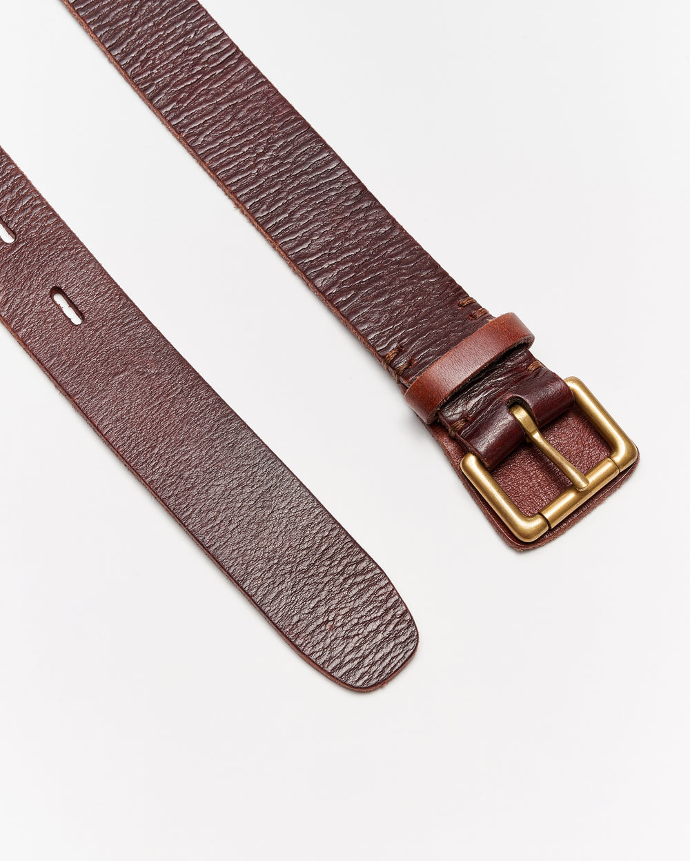 A brown leather belt with a gold rectangular buckle is laid flat on a white surface. One end shows punched holes, while the other end has the buckle attached.
