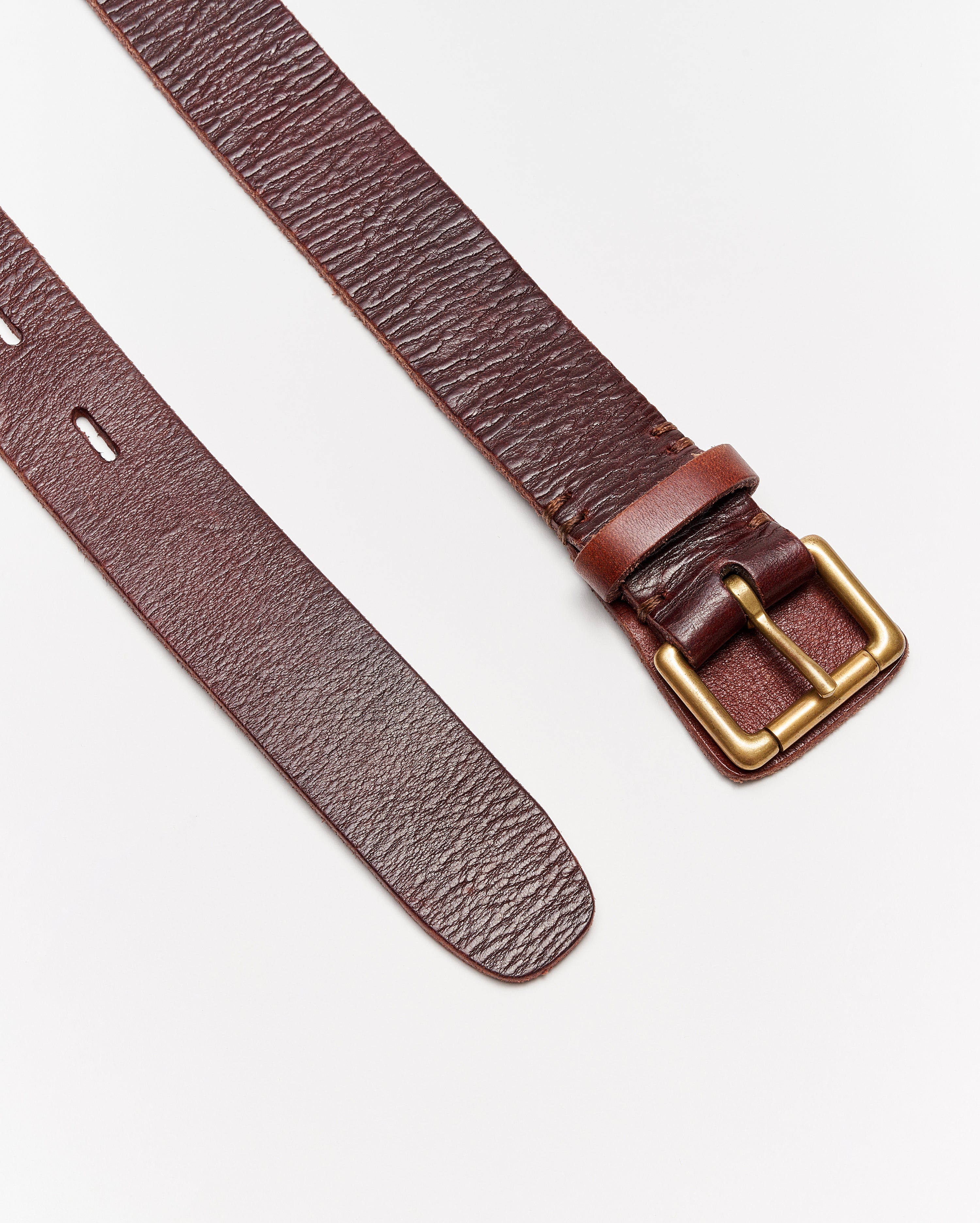 A brown leather belt with a gold rectangular buckle is laid flat on a white surface. One end shows punched holes, while the other end has the buckle attached.