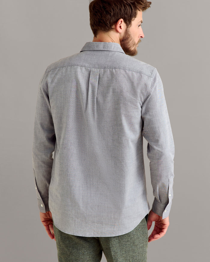 Man wearing a light gray button-up shirt against a plain background