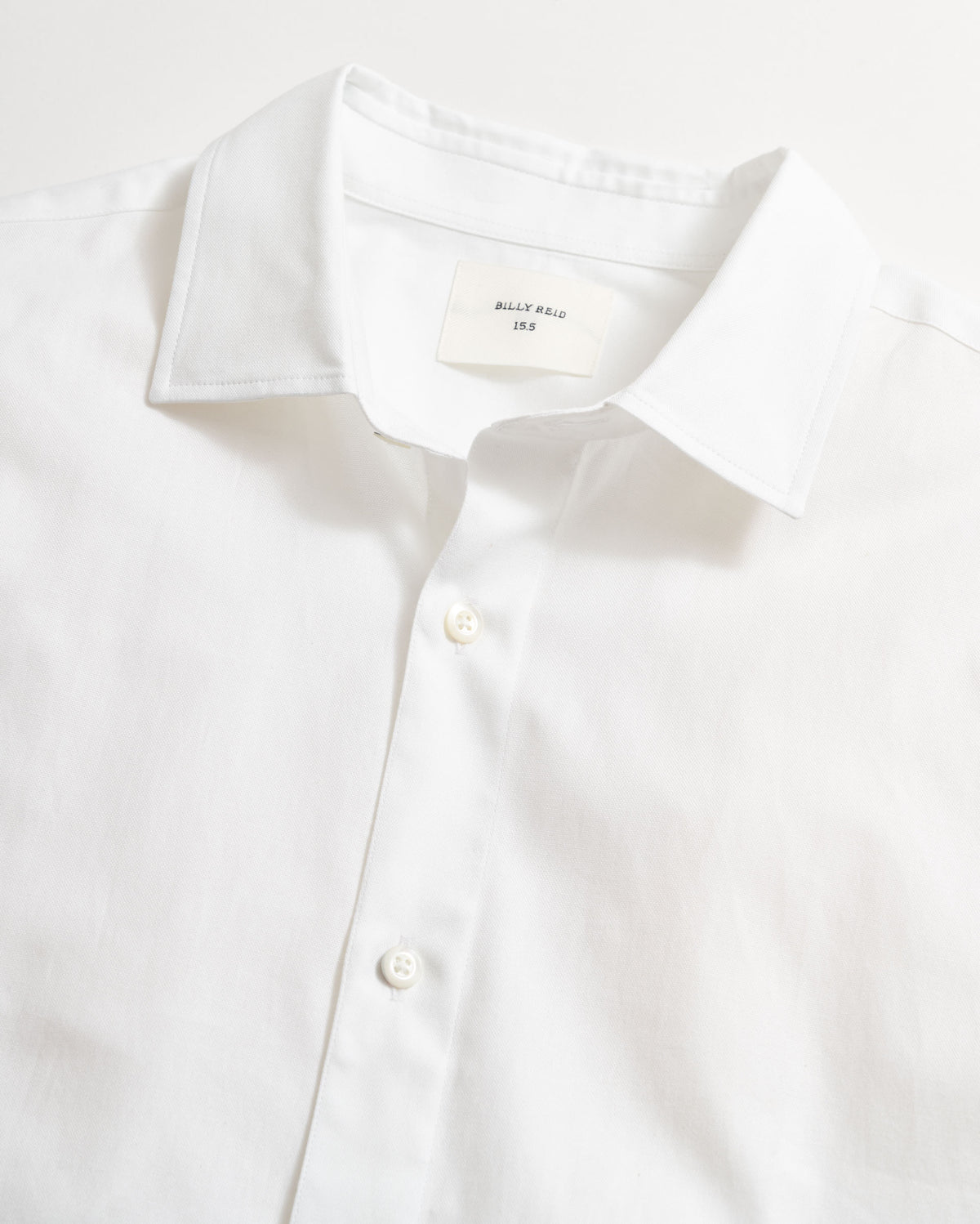 White dress shirt with collar and button details on a light gray background