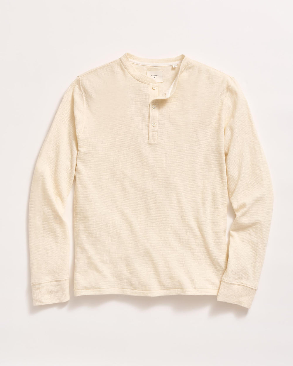 A long-sleeve, cream-colored henley shirt with a round neckline and three buttons down the front, laid flat on a white background.