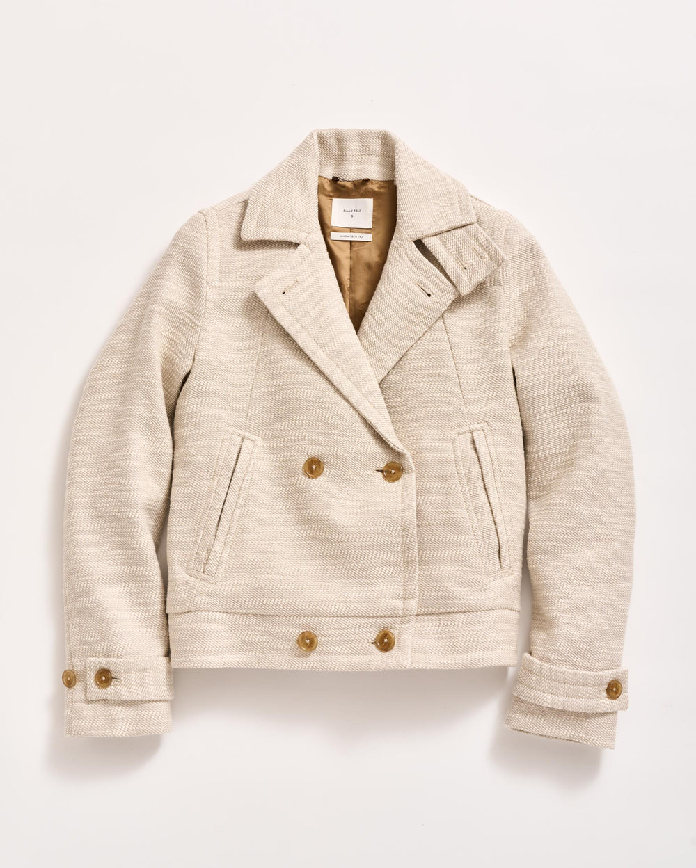 A cream-colored, double-breasted wool jacket with brown buttons, two front pockets, a notched collar, and buttoned cuffs, laid flat on a white background.