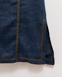 A close-up of a dark blue fabric garment with brown stitched seams and a small side slit near the hemline, photographed against a light background.