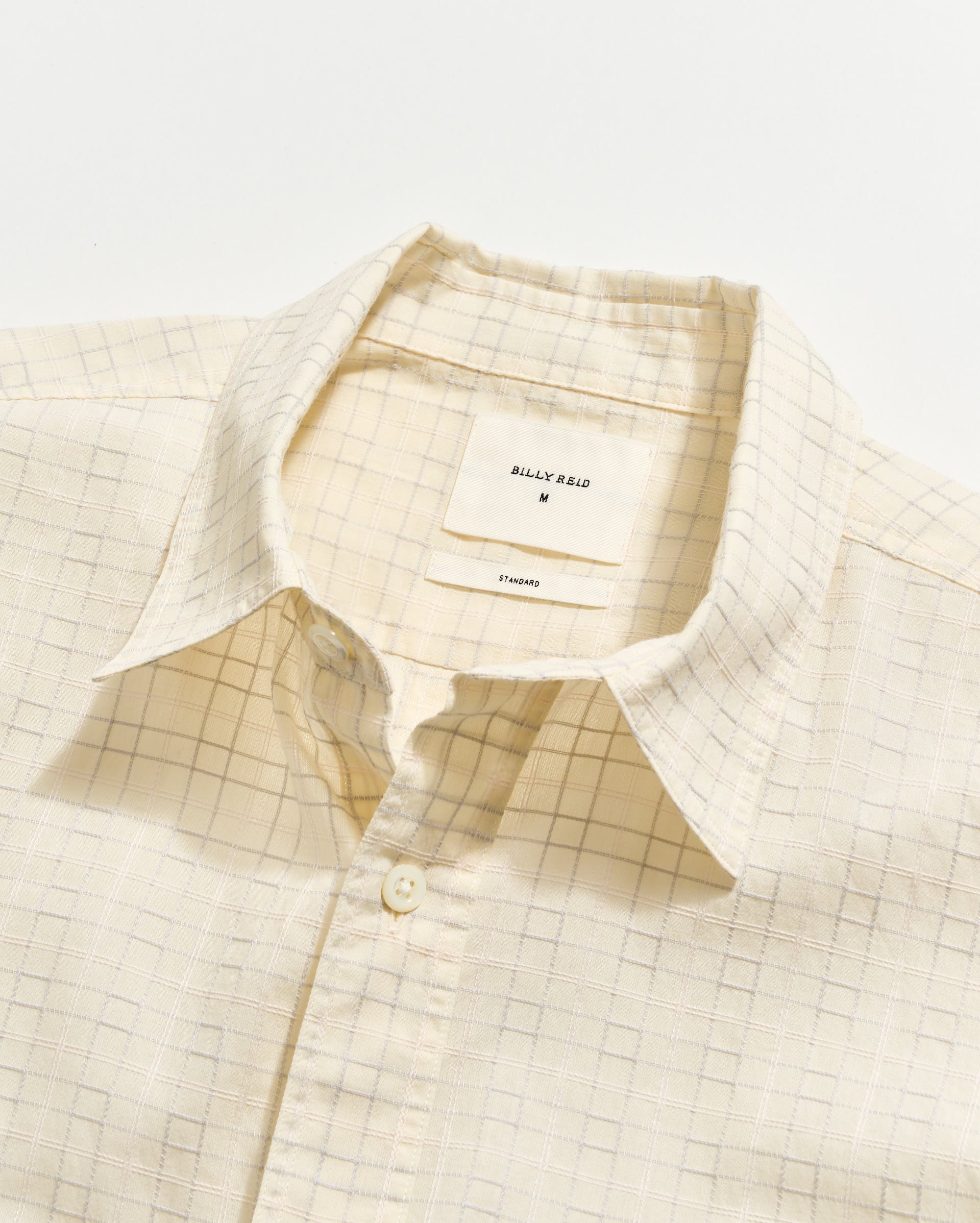 Beige checkered shirt with a brand label on a light background