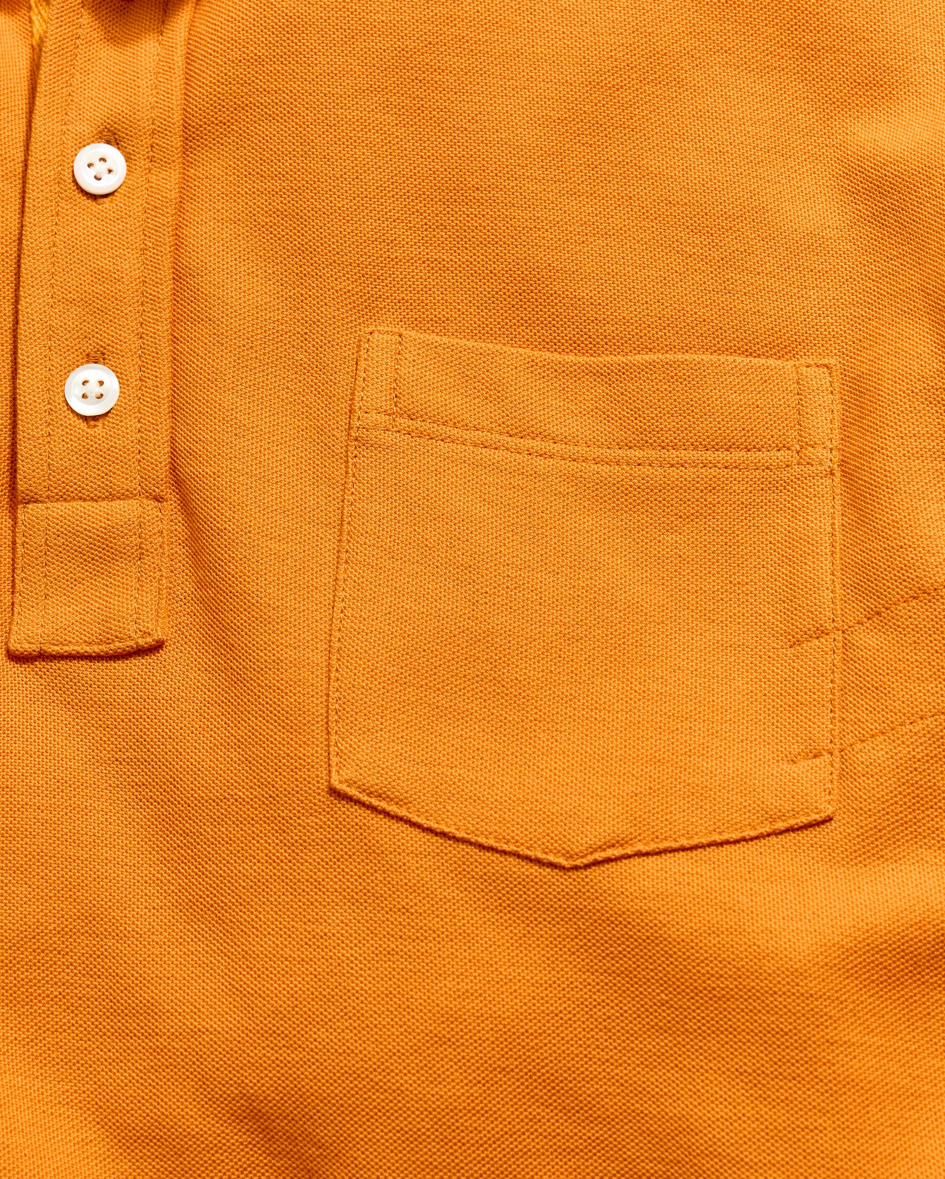 Close-up of an orange shirt with a pocket and buttons.