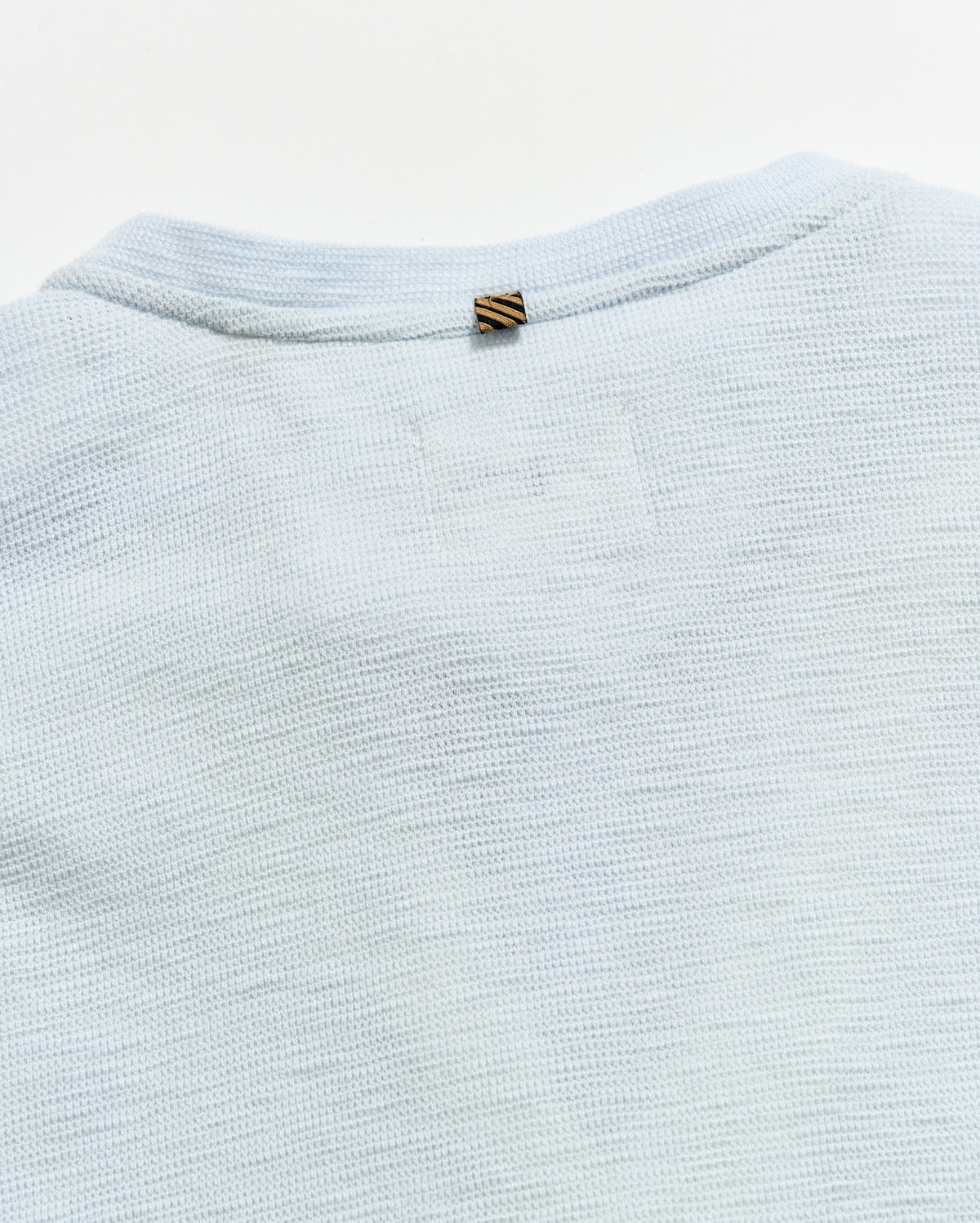 Light blue textured fabric with a brand tag on a white background