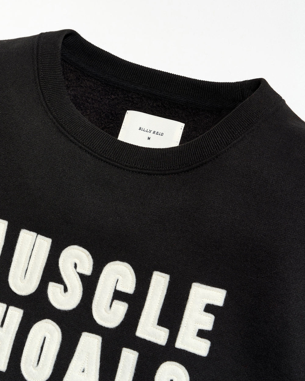 Black t-shirt with 'MUSCLE SHOALS' text and a visible brand label on a white background