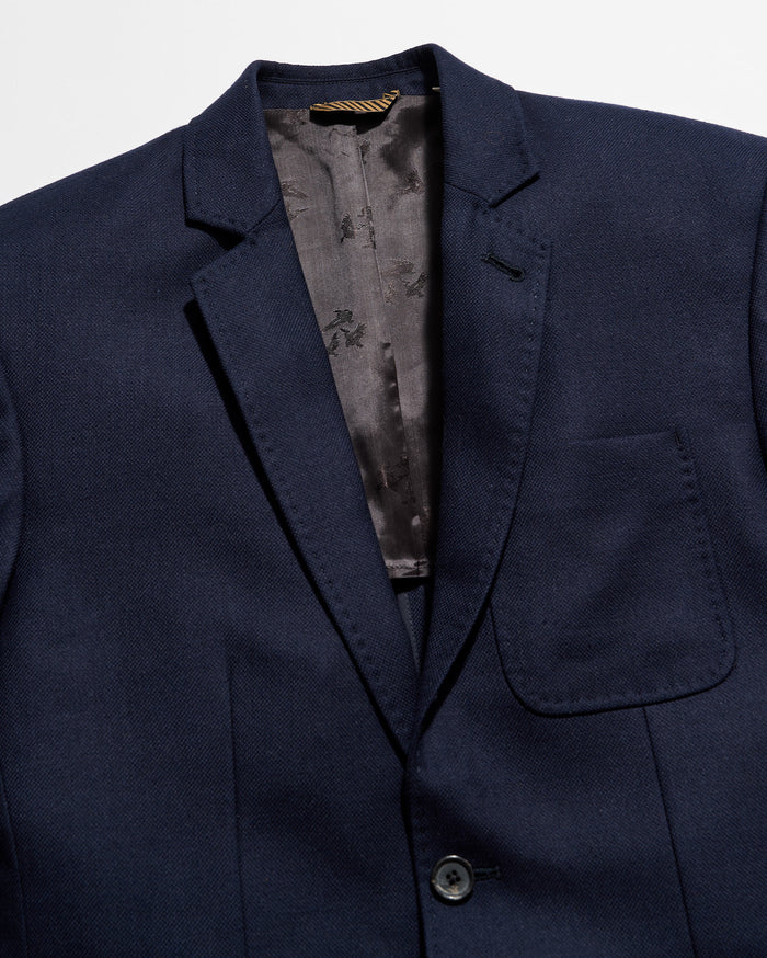 Navy blue blazer with a floral patterned lining on a light gray background